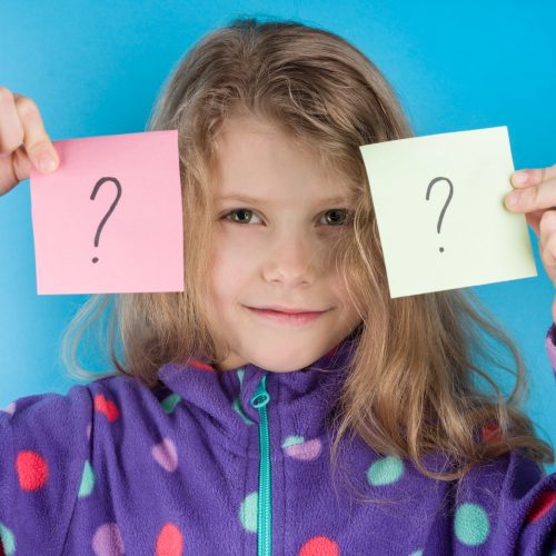 Child girl holding stickers with question marks